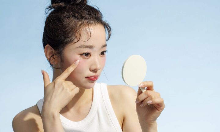 손거울로 얼굴 좌우를 살펴보는 여성
