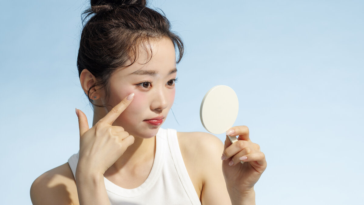 손거울로 얼굴 좌우를 살펴보는 여성